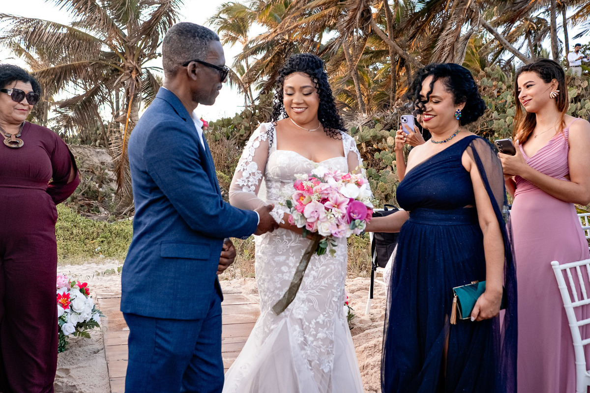 Noivo recebendo a noiva no altar durante cerimônia de casamento na praia em Salvador