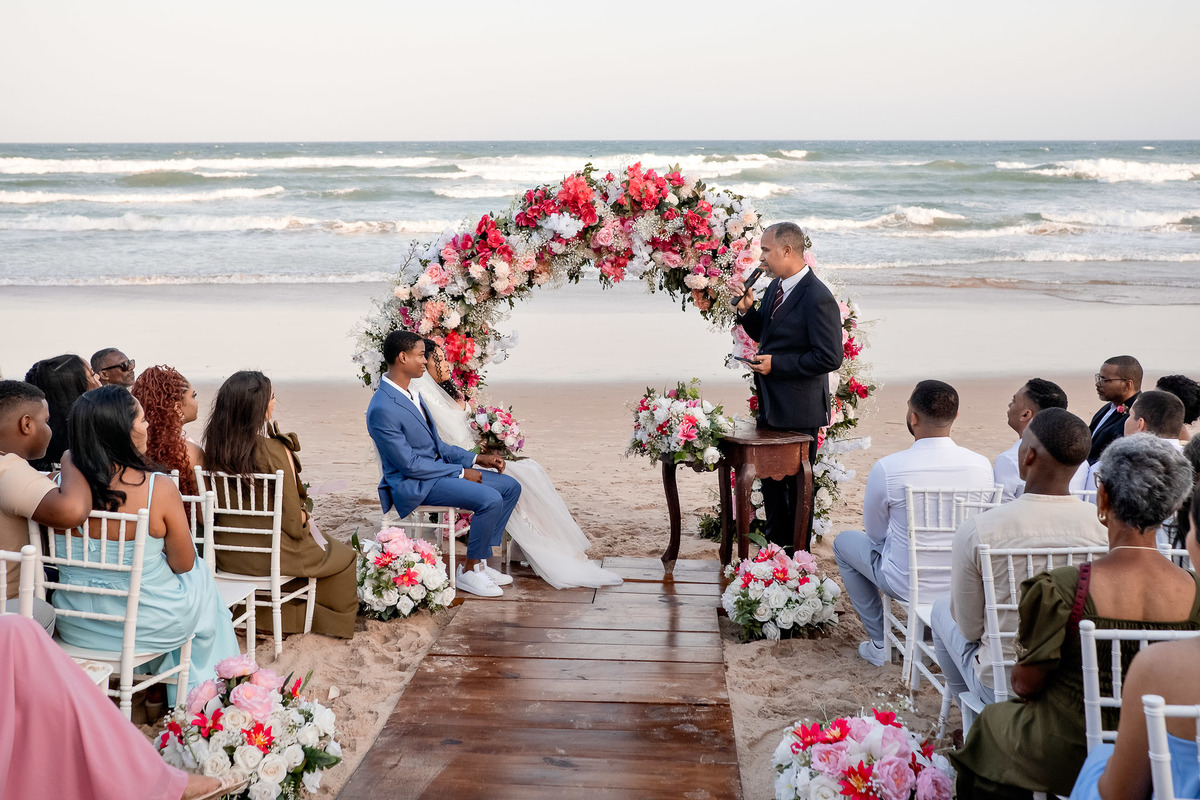 Vista geral da cerimônia de casamento na praia com arco de flores em Salvador