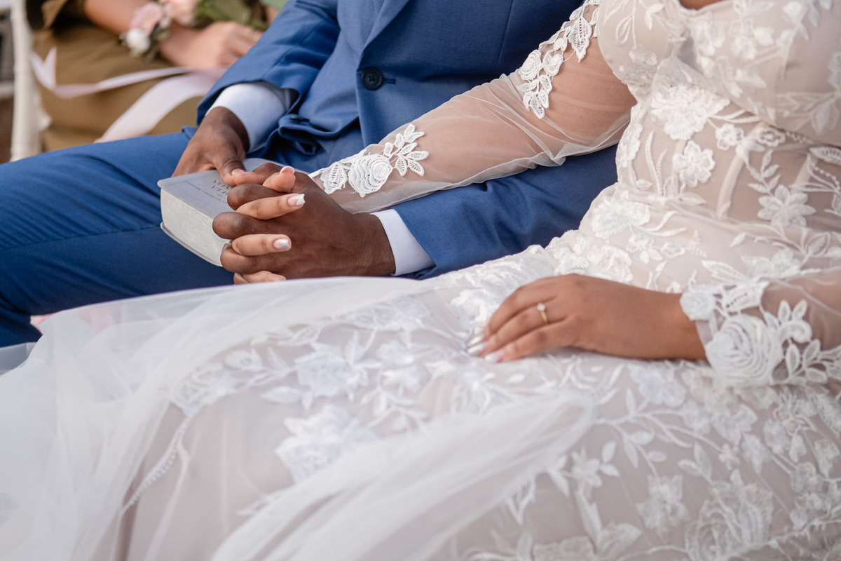 Detalhe das mãos do casal durante a cerimônia de casamento na praia em Salvador