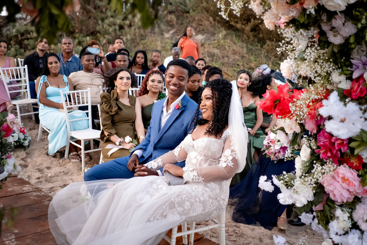 Casal sentado ao lado da família durante a cerimônia de casamento na Praia do Flamengo