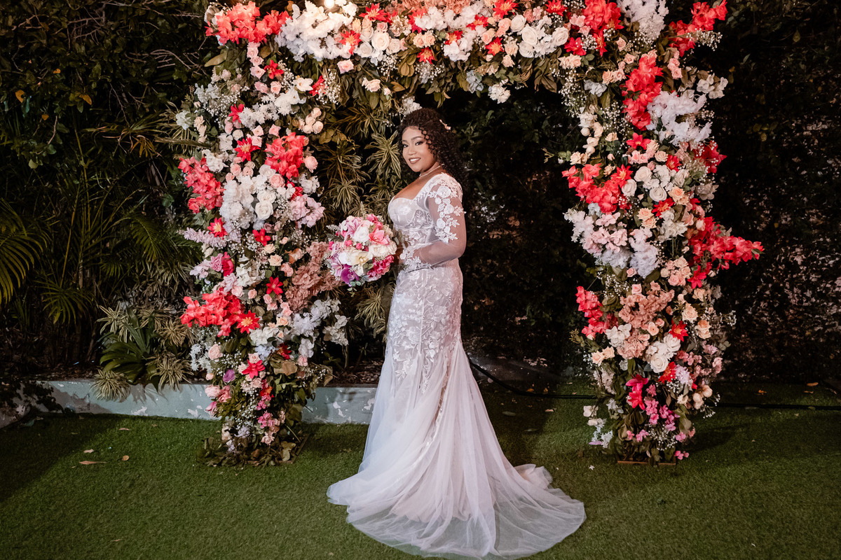 Noiva posando sob arco de flores no jardim da festa de casamento em Salvador