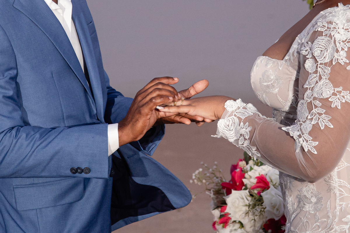 Detalhe da aliança sendo colocada durante cerimônia de casamento na praia em Salvador