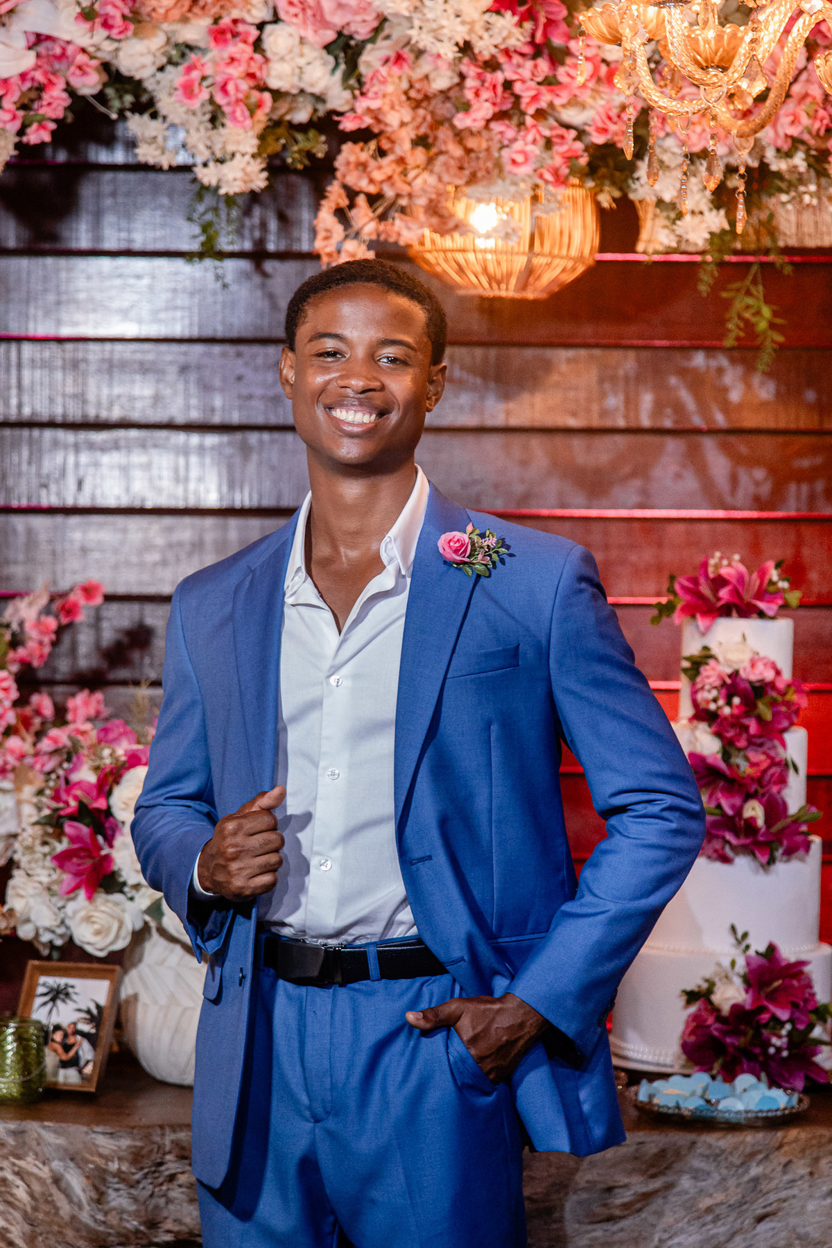 Noivo em retrato noturno com arranjo floral ao fundo na festa de casamento em Salvador