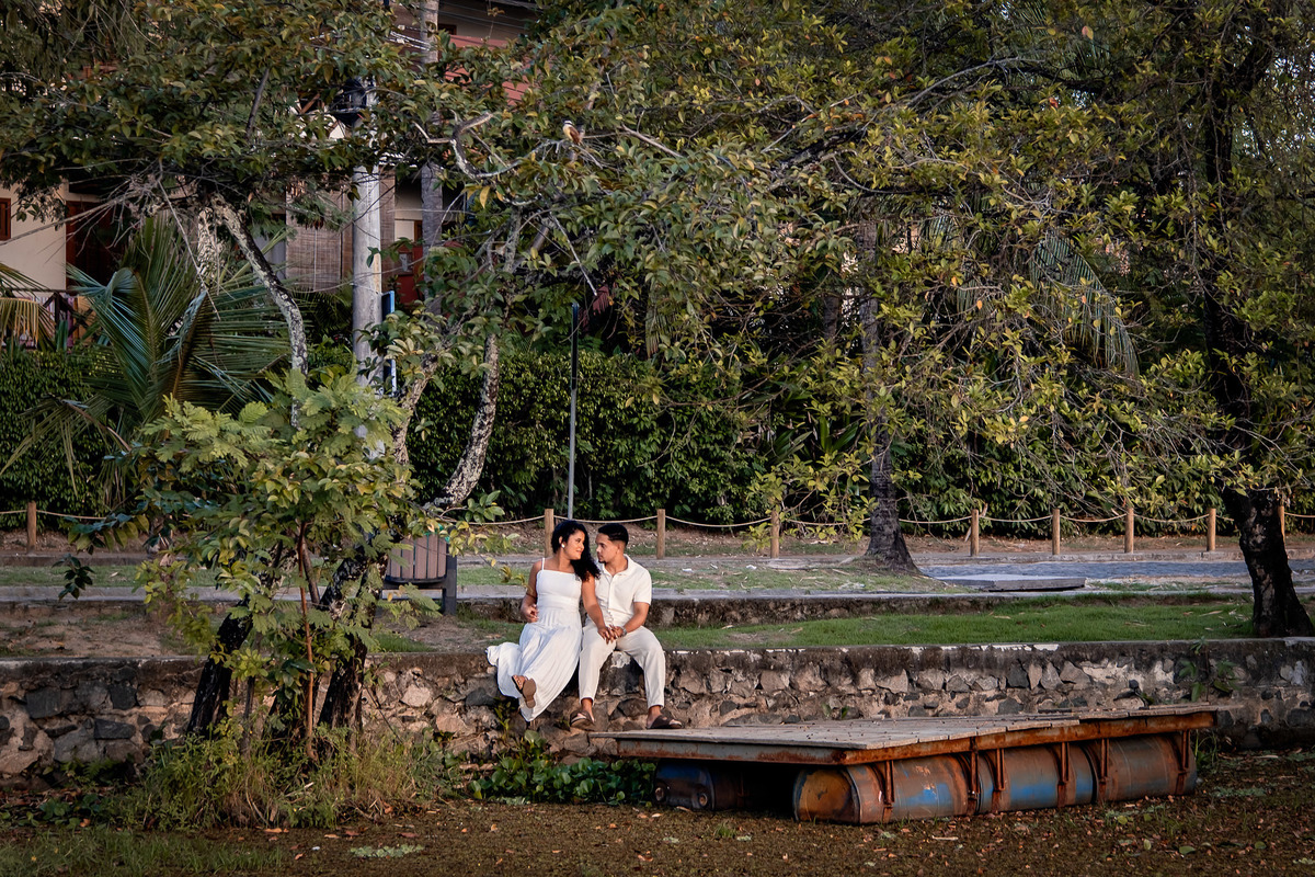 Noivos sentados à beira do píer no ensaio pré-casamento na Praia do Forte, Bahia