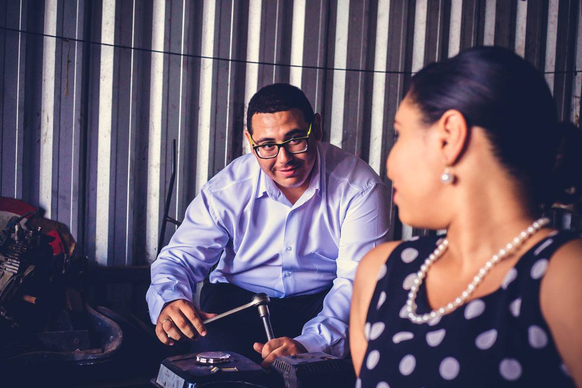 foto de casal com noivo consertando carro e noiva olhando para ele