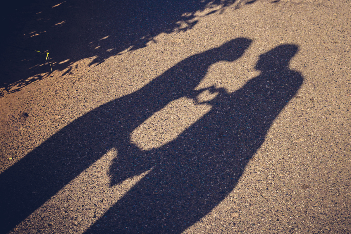 fotografia de casal com silhueta na sombra fazendo coração na mão