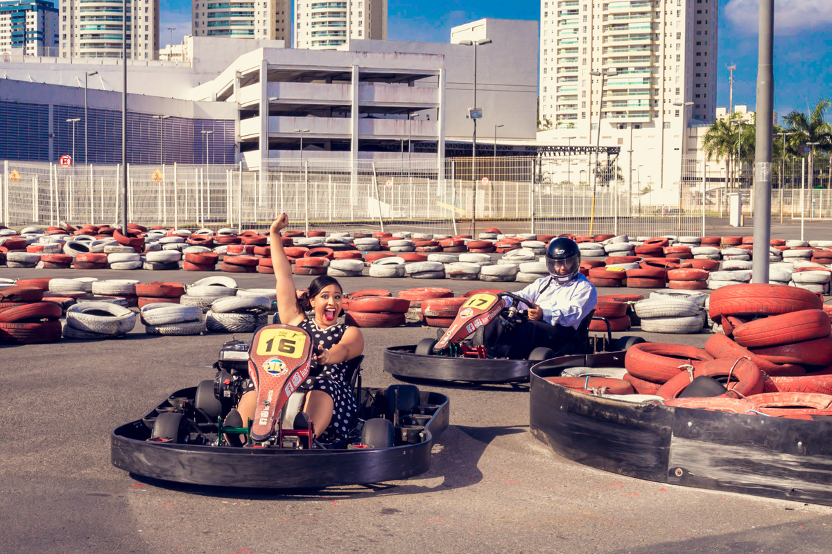 noivos pilotando kart com noiva de braço pra cima comemorando sua vitória