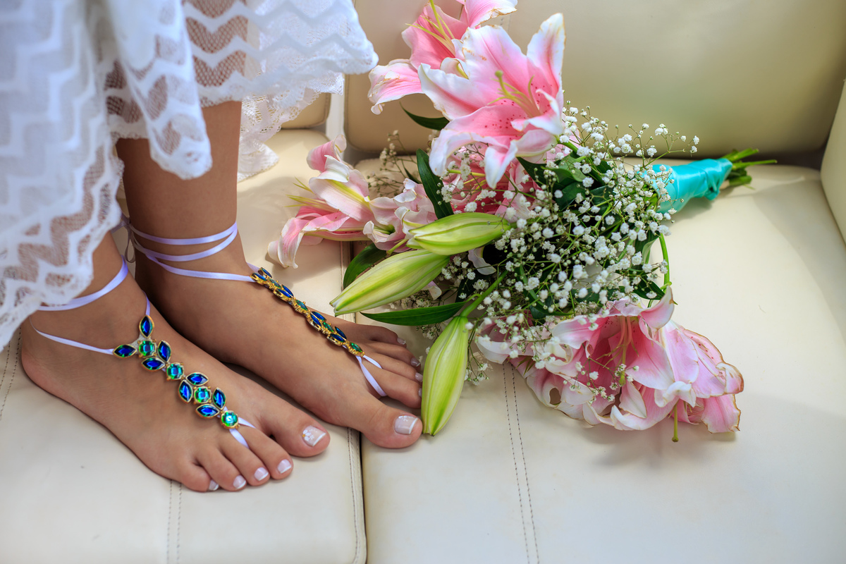 sandálias de pés descalços nos pés da noiva junto com o buque