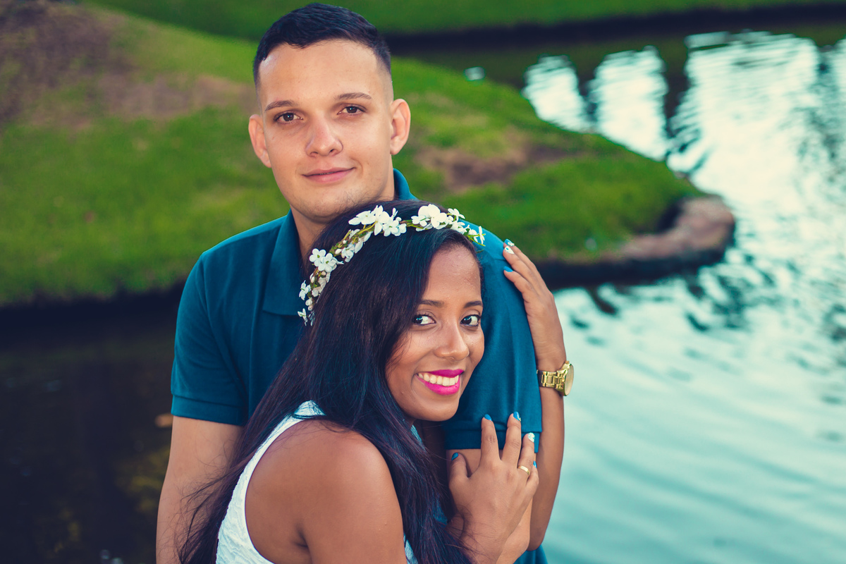 noiva abraçando o braço do noivo em um lago