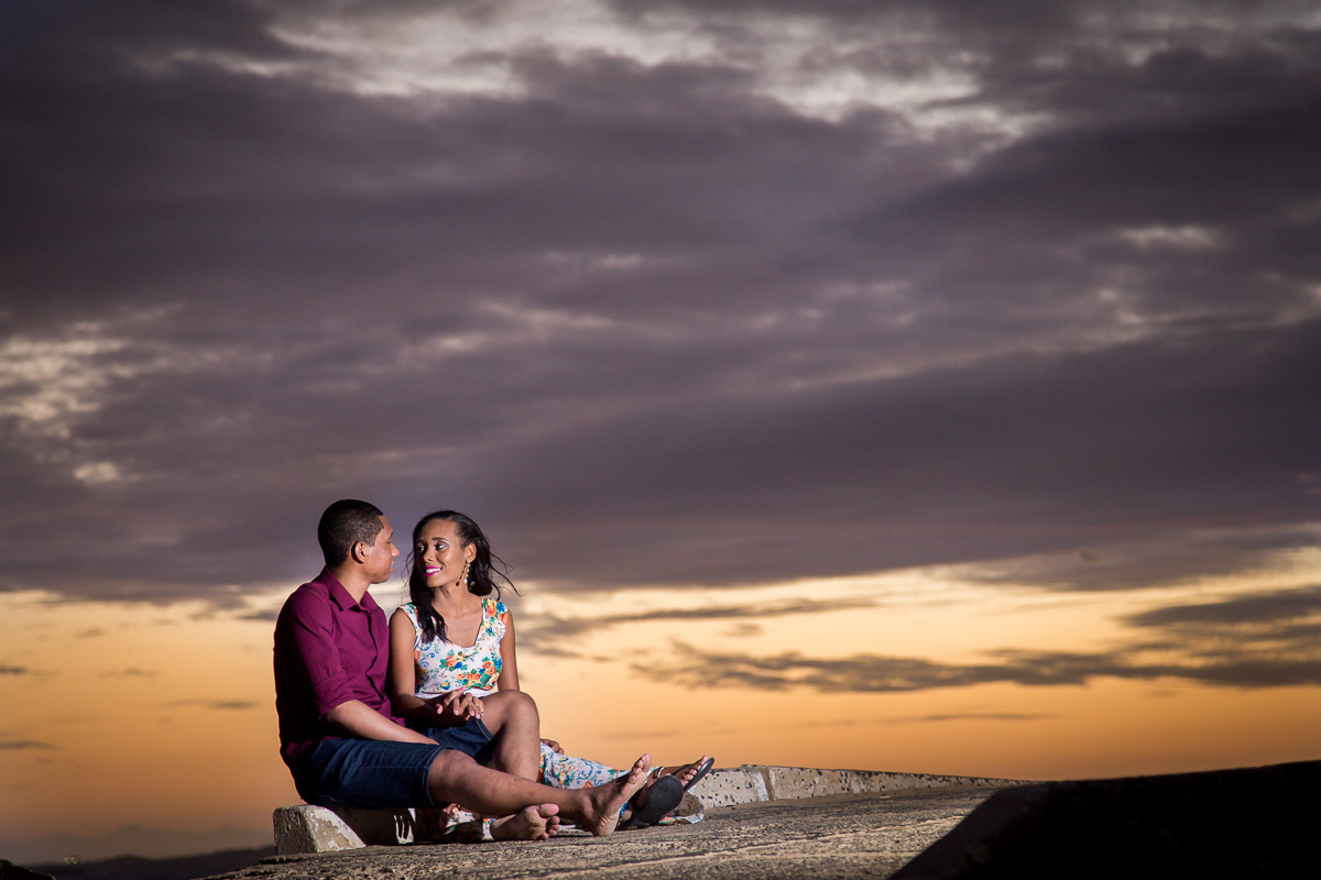 fotografia de casal apaixonado sentados ao por do sol