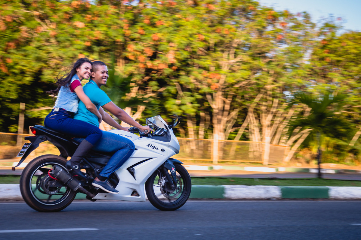 casal em ensaio divertido na praia de Guarajuba pilotando uma moto em um ensaio fotográfico