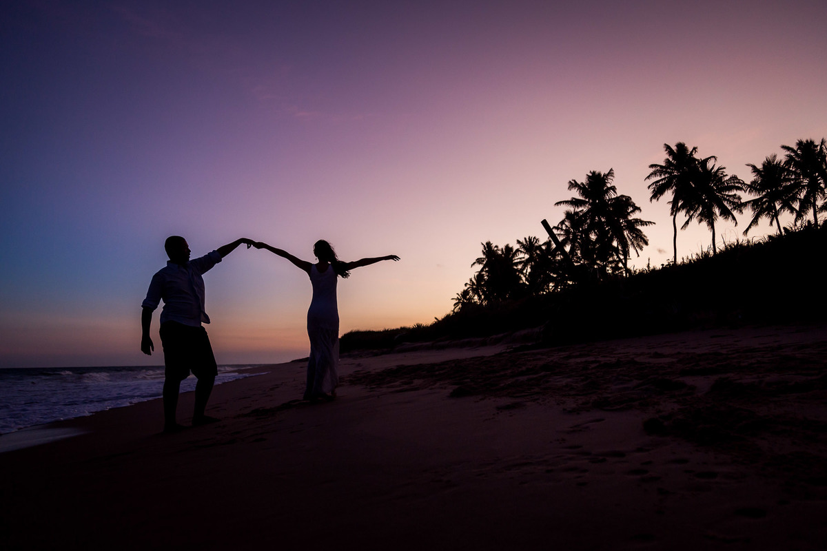 fotografia de silhueta de casal com a sombra aparecendo no lindo por do sol com coqueiros no fundo da imagem