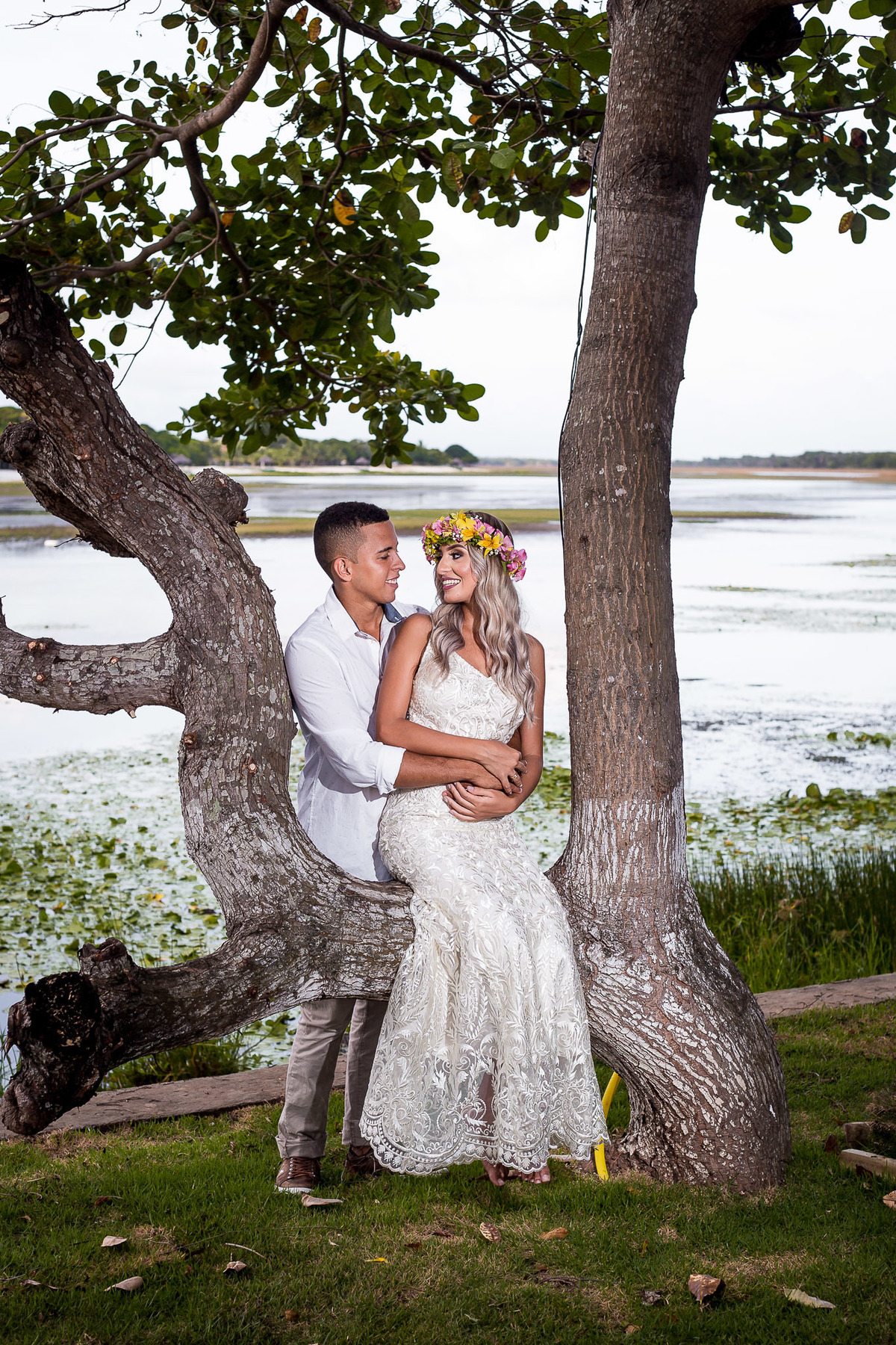 casal sentado em uma árvore com um rio no cenário de fundo na praia de Guarajuba - Bahia
