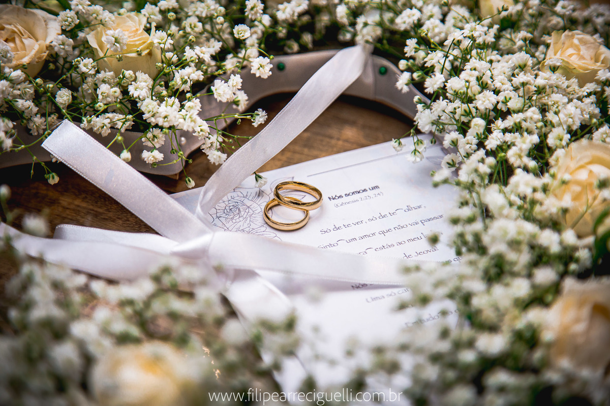 Foto das alianças dos noivos em um porta aliança de flores