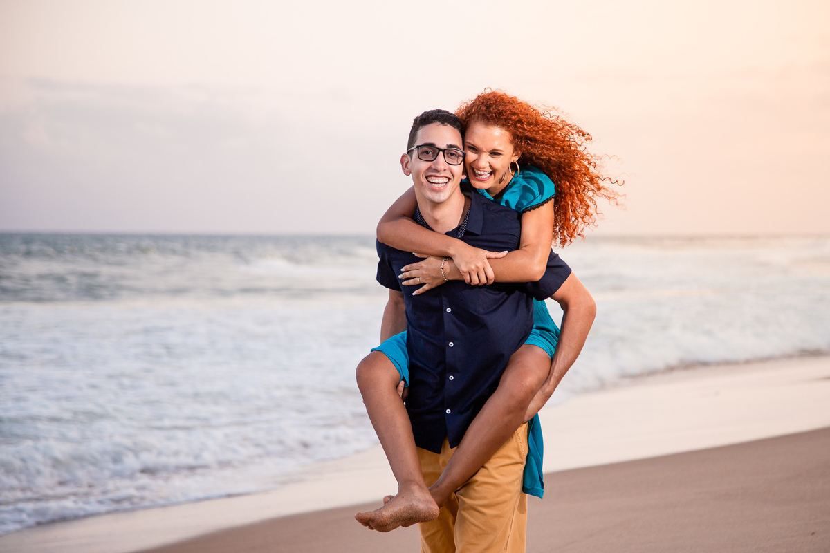 Ensaio fotográfico na praia de Vilas do Atlântico com pose de cavalinho e noivos sorrindo