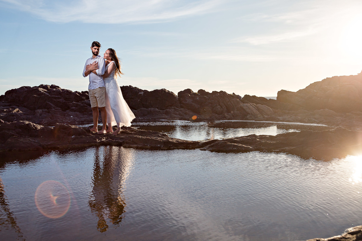 fotografia de reflexo com casal abraçados na praia a luz do sol
