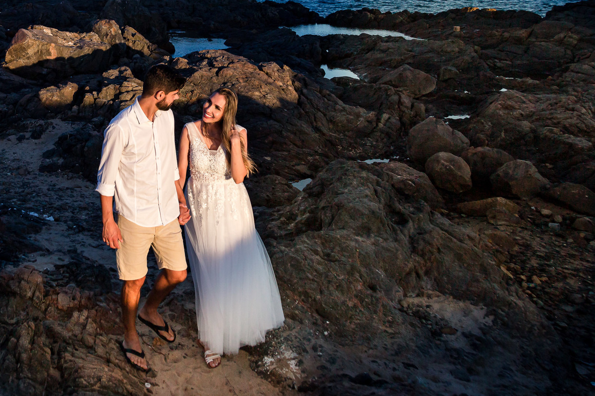 Fotografia de casal caminhando na praia da Barra ao por do sol