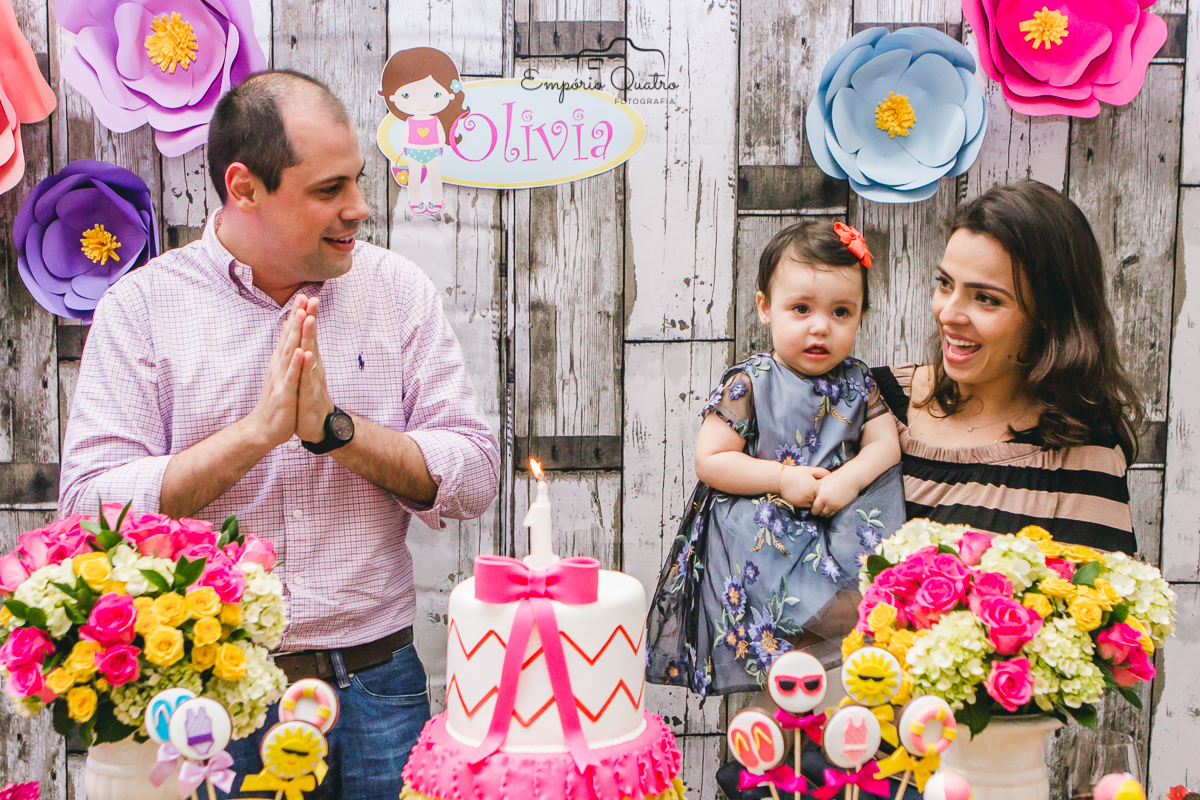 fotografia aniversário aniversariante na mesa do bolo com seus pais na hora do parabens com a decoração no tema praia