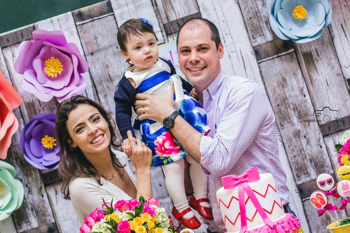 fotografia aniversário aniversariante no colo de seus pais sendo levantada na mesa do bolo decorada no tema praia