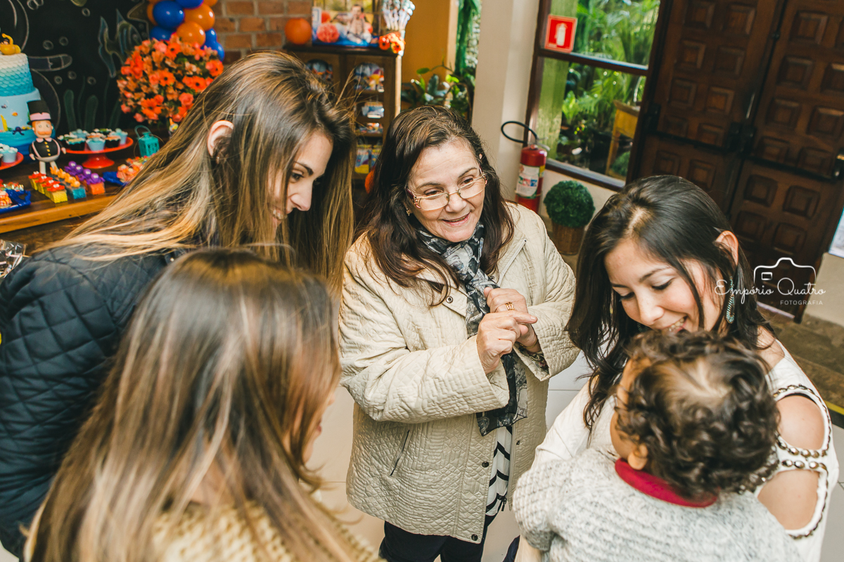 Aniversariante rodeado de convidadas brincando com ele