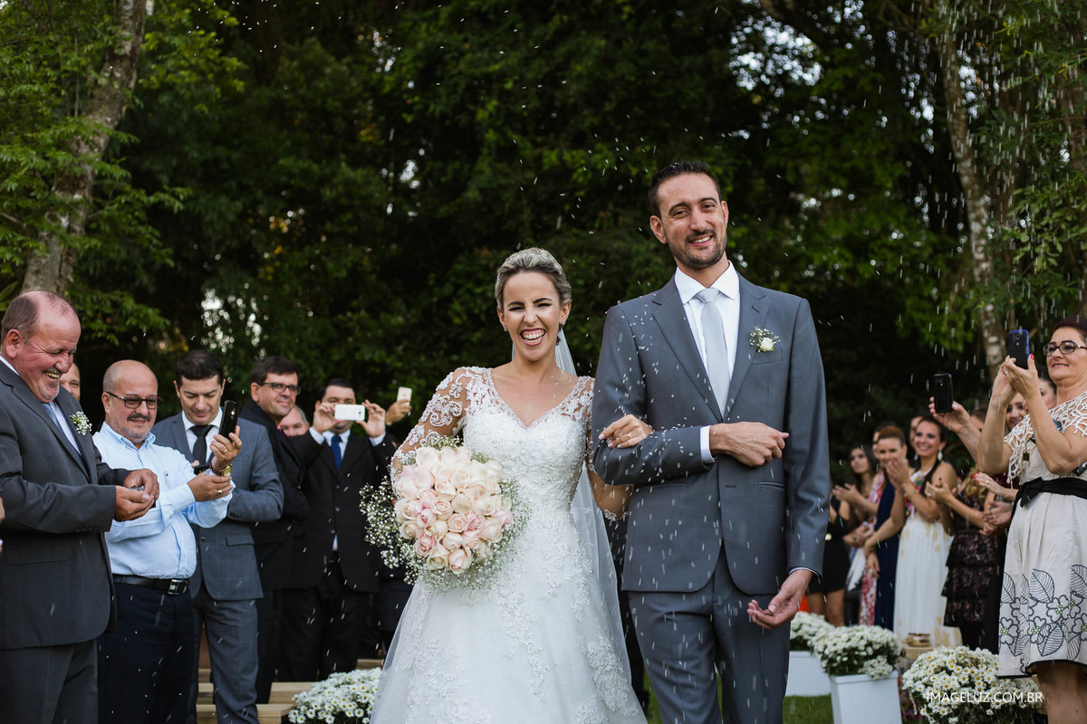 Noivos saindo da cerimônia e sendo jogado arroz neles.