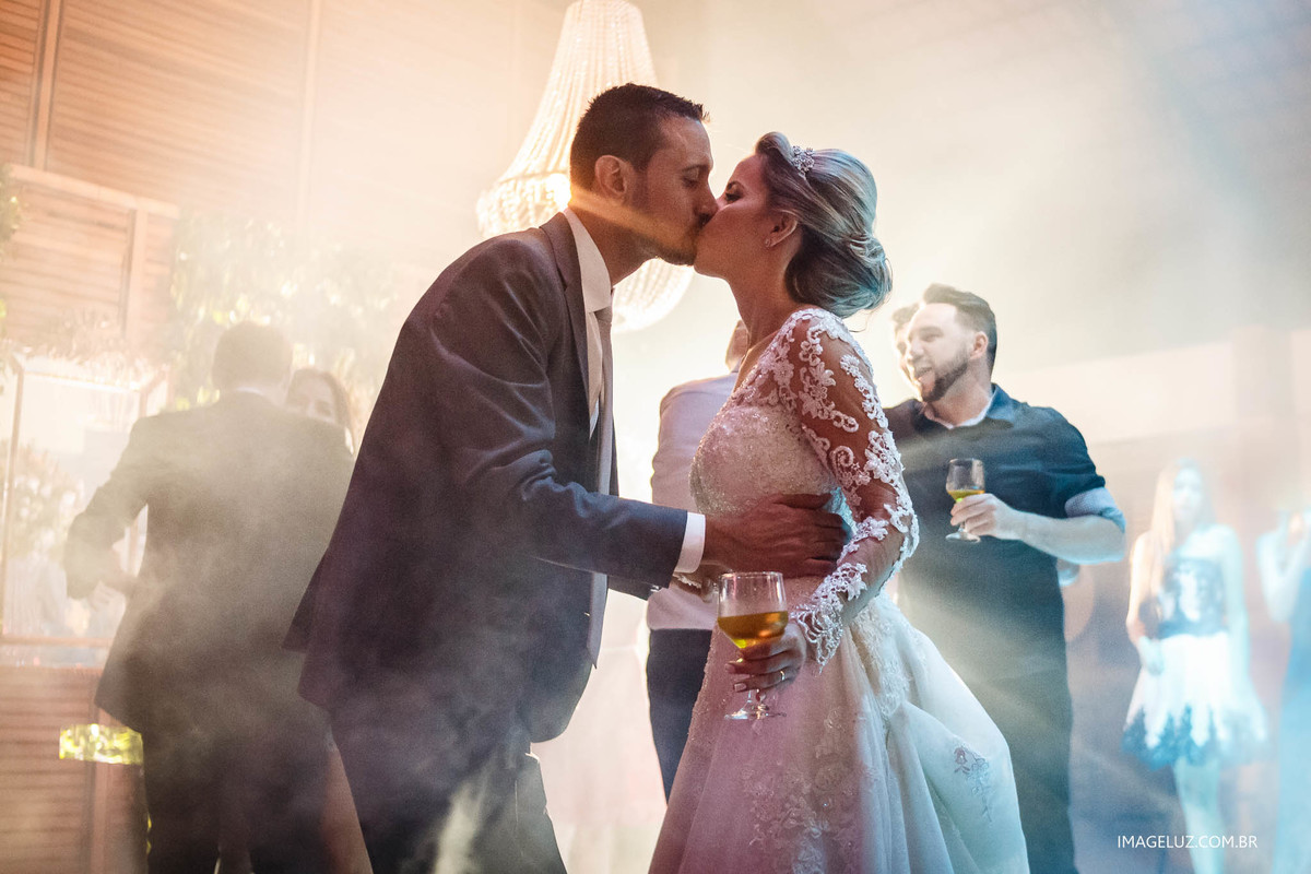 Beijo dos noivos no meio da festa, com uma luz incrível.