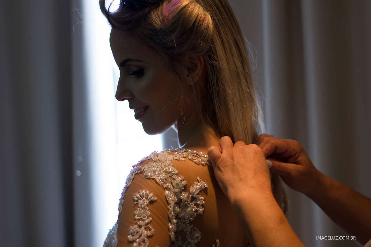 As resndar do vestidos destacadas pela luz, e um belo sorriso da noiva.