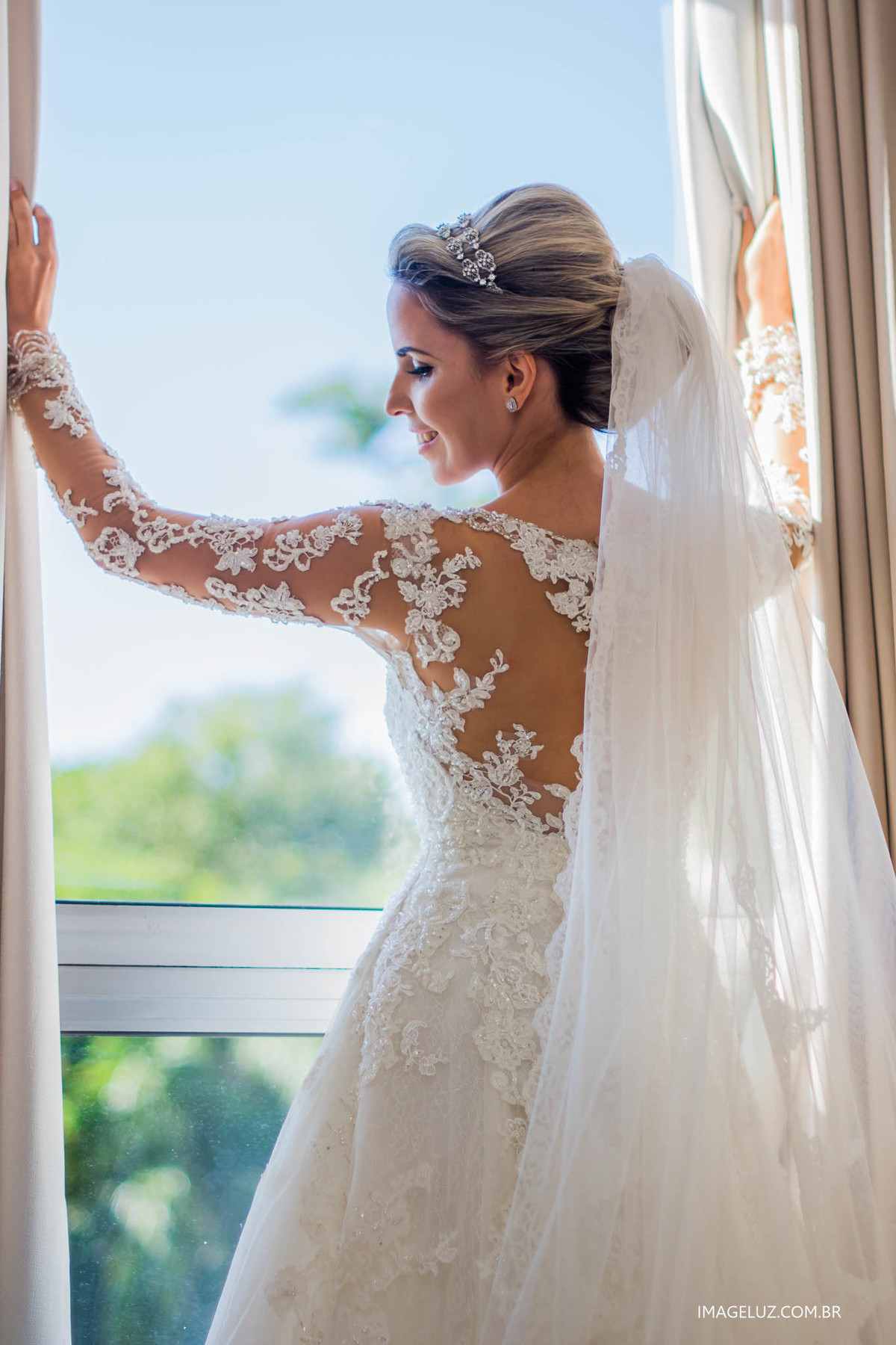 Noiva na janela mostrando os detalhes do seu vestido. #fotografoemcuiaba