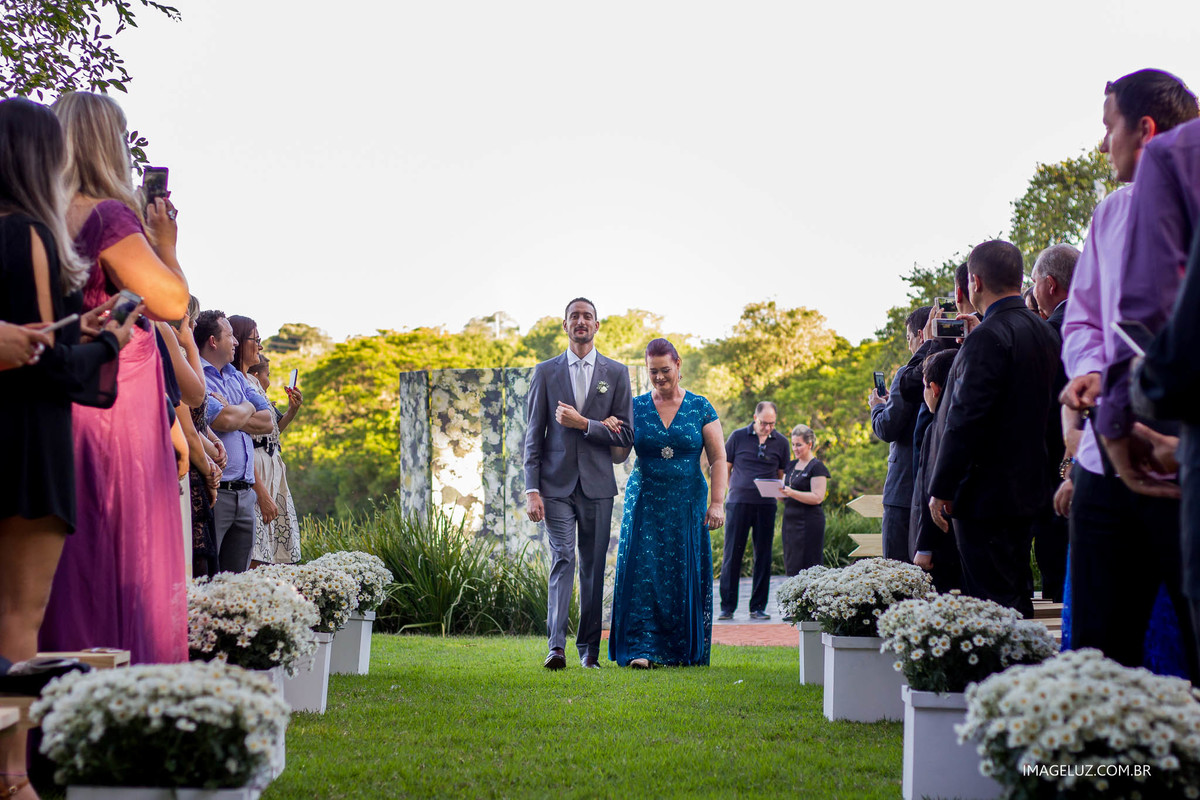 A entrada do noivo ao lado de sua mãe.