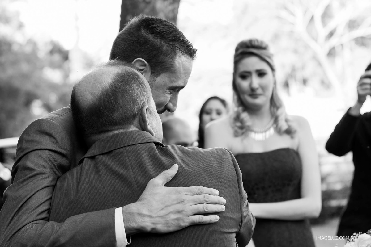Noivo abraçando o pai da noiva no altar.