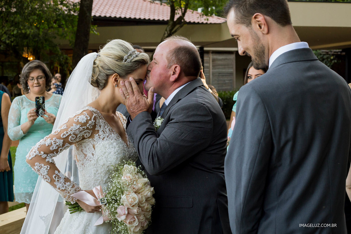 Pai da noiva beijando a testa da noiva em frente ao altar.