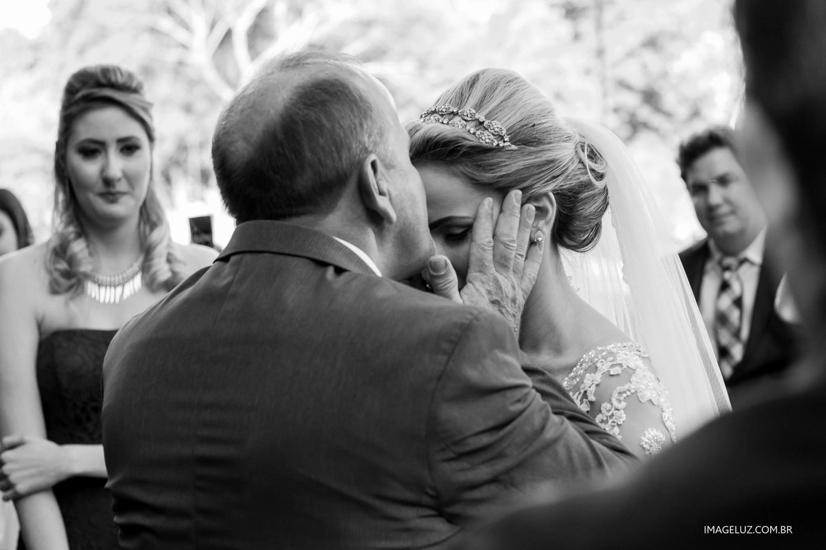 Filha sendo beijada na testa em seu casamento, por seu pai, ao leva-la até o altar.