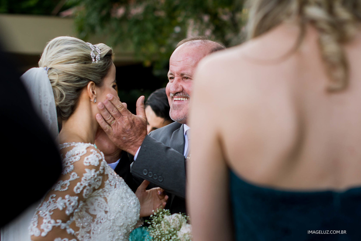 O sorriso do pai da noiva ao entrega-la a seu noivo no altar.