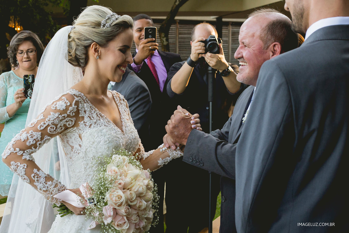 Pai e filha apertando as mão em seu casamento, em frente ao altar.