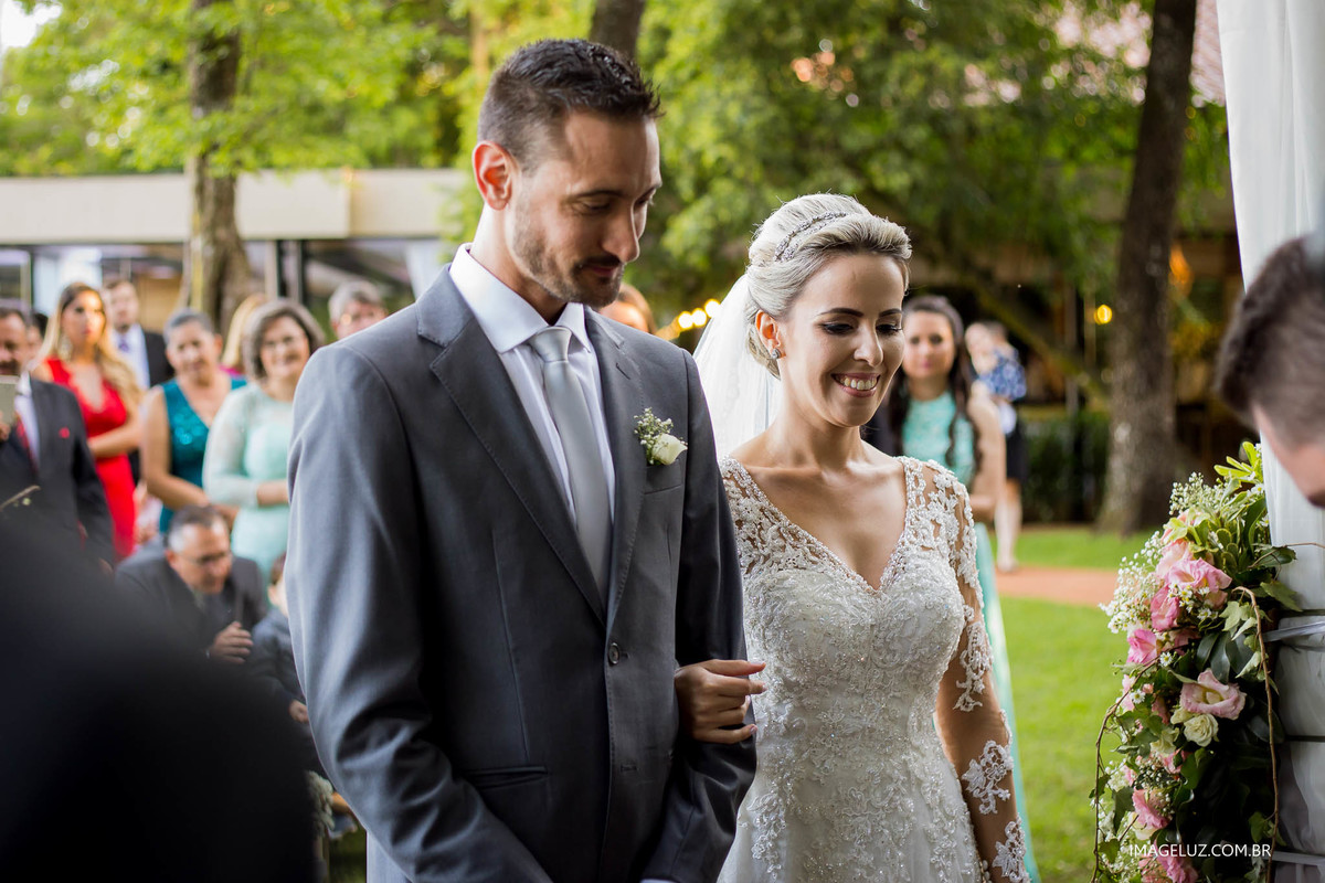 Noivos em frente ao altar sorrindo, e mostrando a felicidade que estão sentindo.