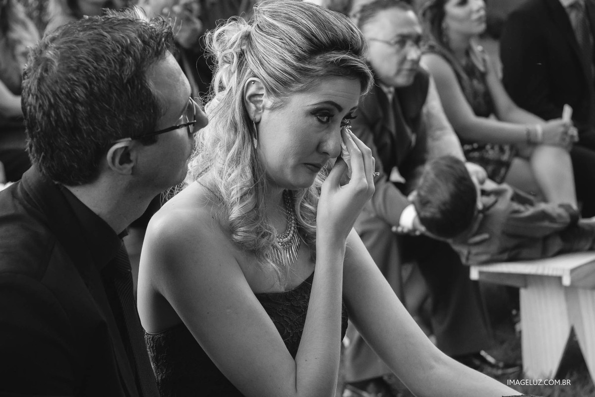 Irmã do noivo chorando de emoção, na hora dos votos do casamento.