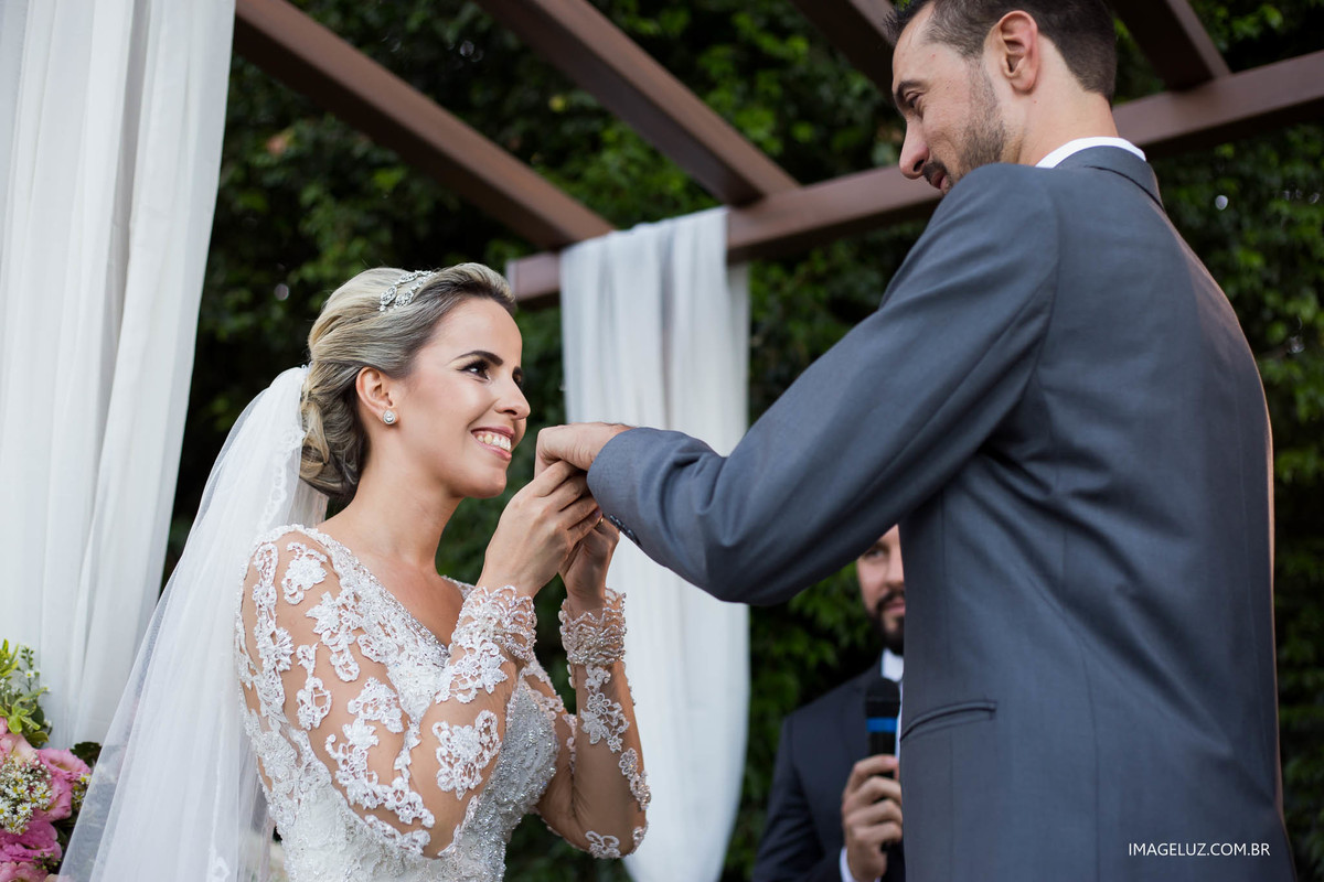 Noiva beijando a mão do noivo e sorrindo. Fotógrafo em cuiabá.