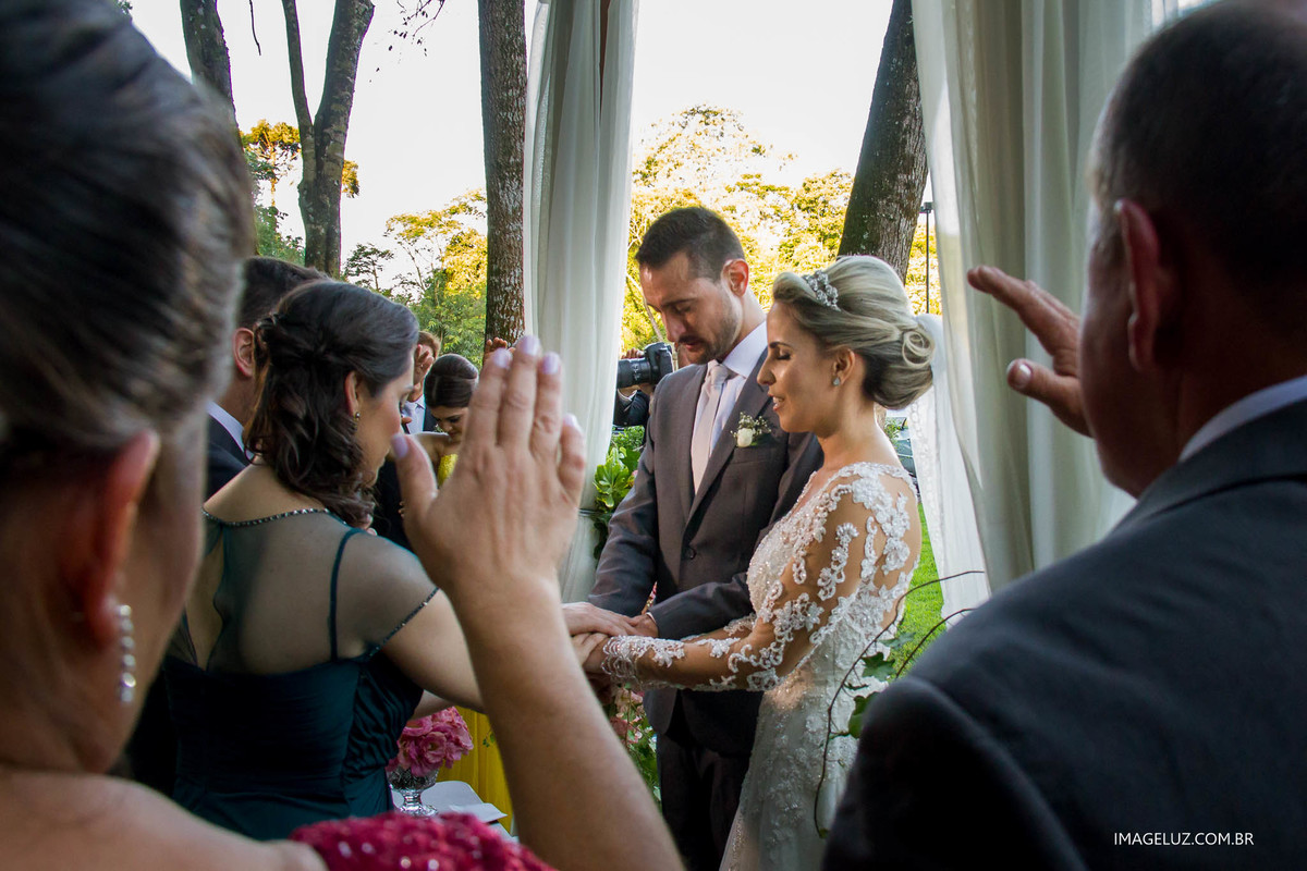 Padrinhos abençoando os noivos em oração.