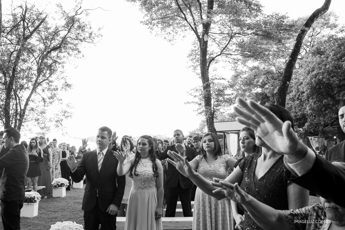 Convidados com as mãos estendidas para abençoar os noivos em oração.