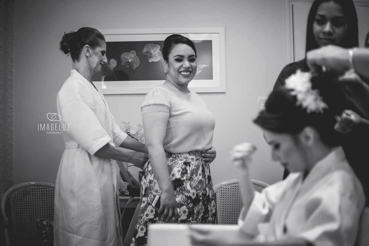 Mão da noiva ajudando a fechar a saia da convidada, que pe mãe da daminha.