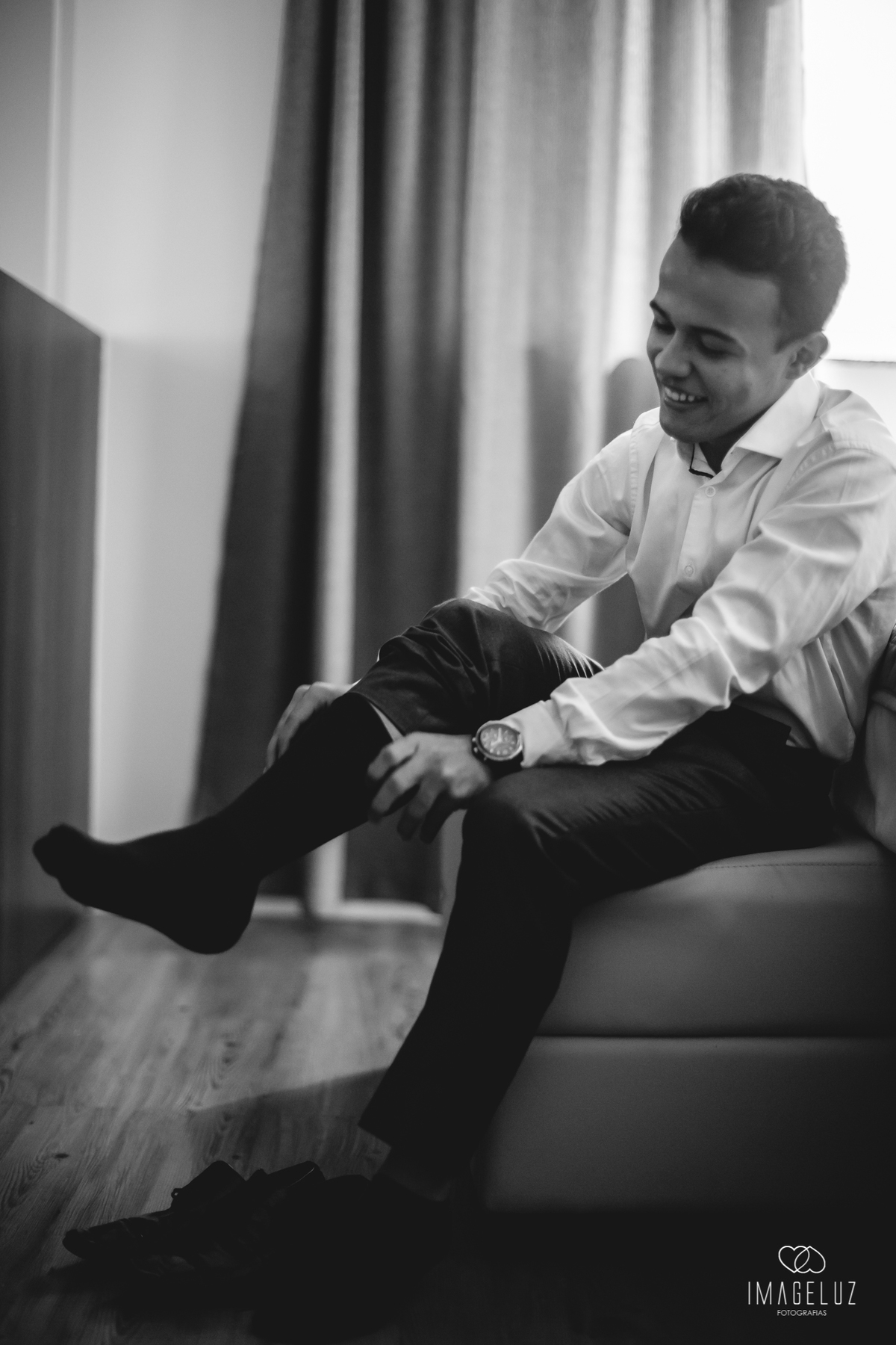 Noivo vestindo a meia, e dando risada.