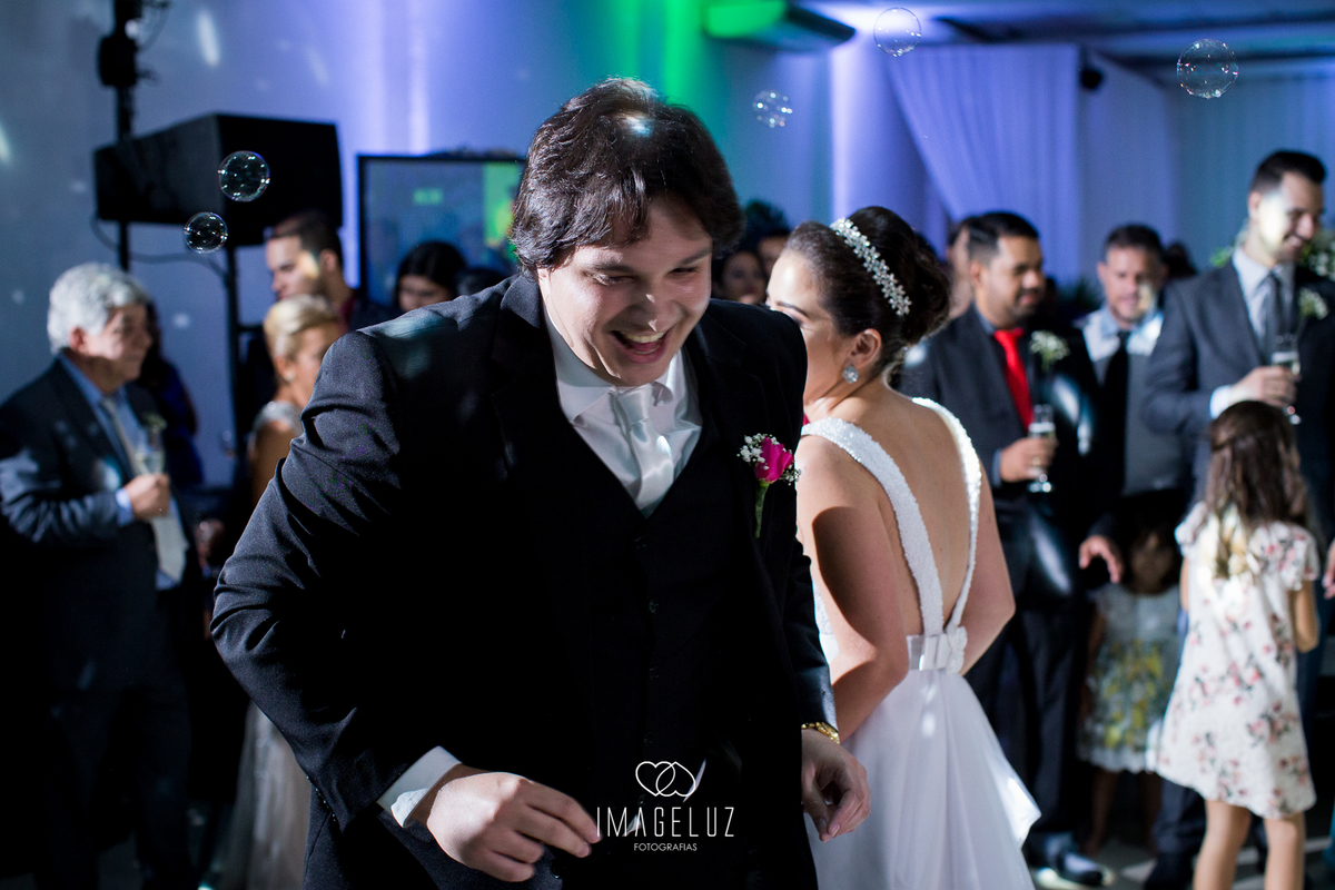 Noivo sorrindo ao dançar no seu casamento.