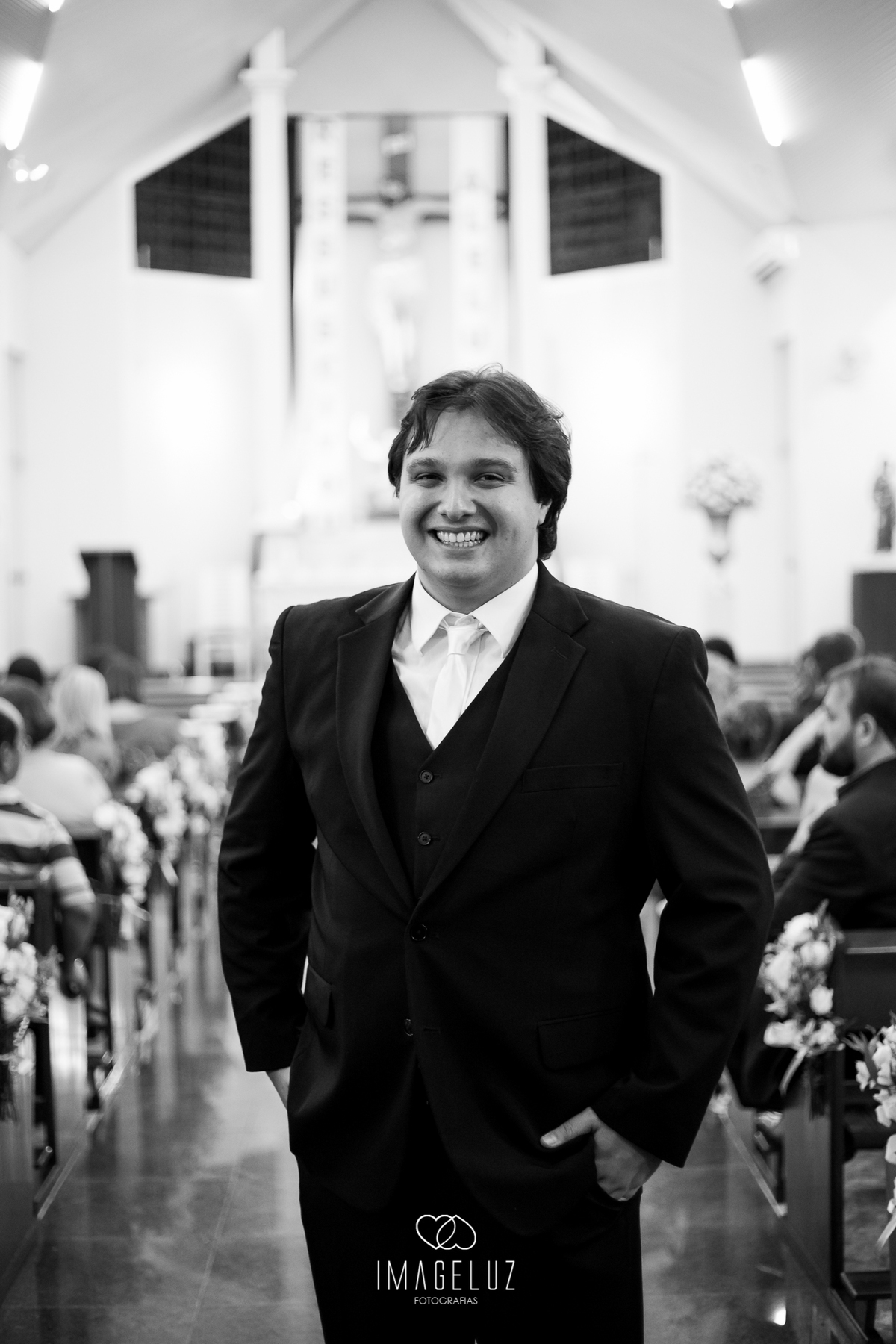 Noivo recepcionando os convidados na igreja, sorridente e feliz.