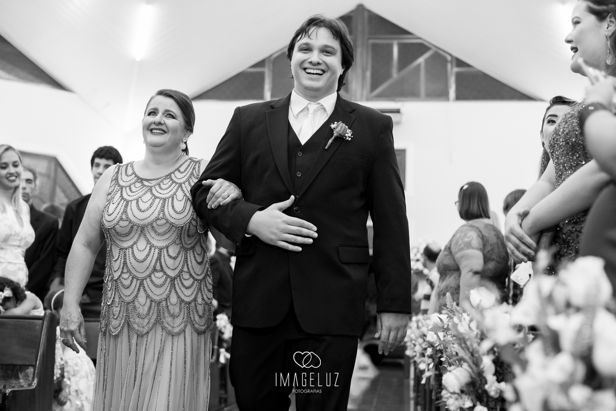 Noivo entrando na igreja com sua mãe ao seu lado. 