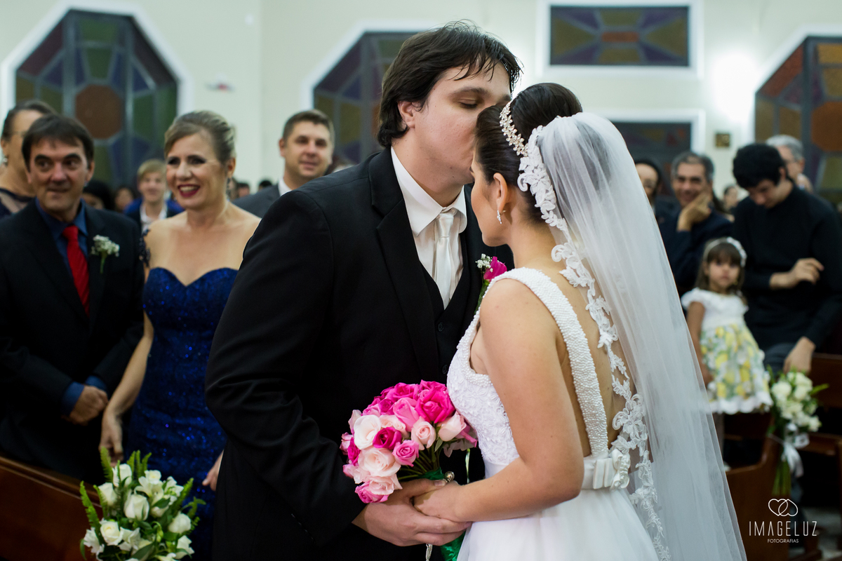 Noivo beijando a testa da noiva em frente ao altar.