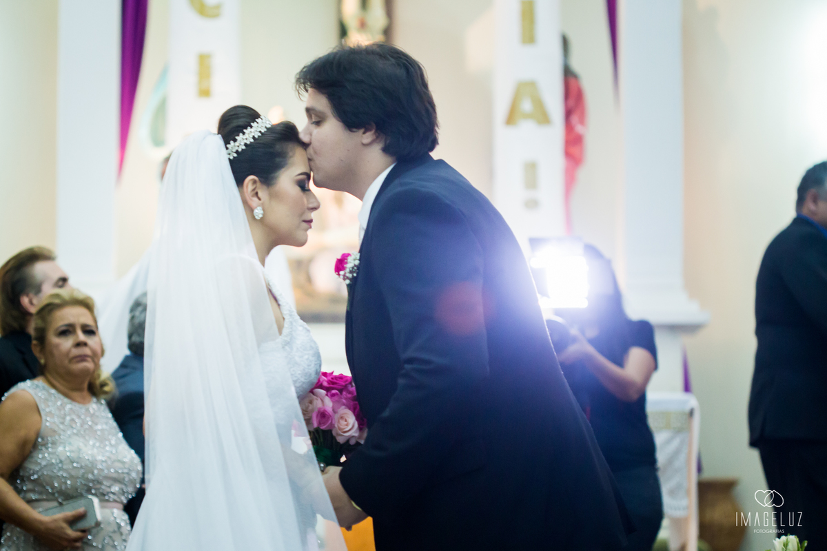 Noivo beijando a testa da noiva.