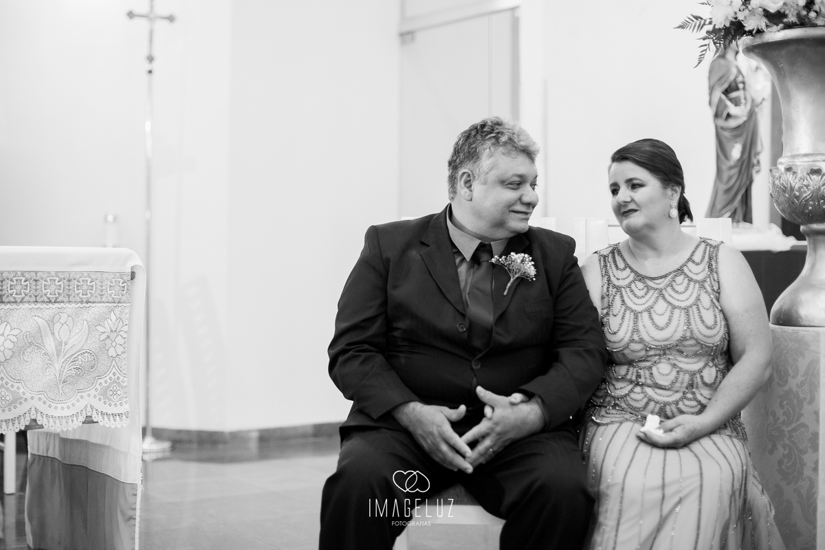 Pais do noivo sorrindo no casamento.