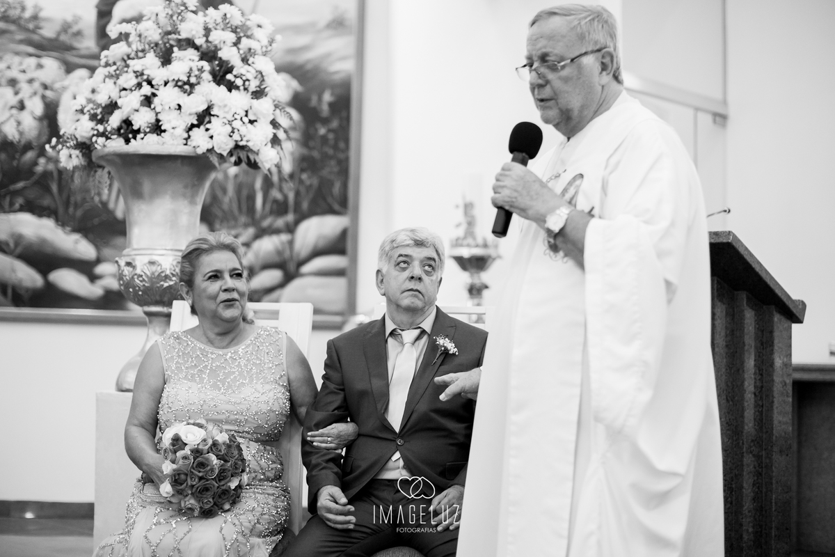 Padre fazendo brincadeira com os pais da noivas, no meio da cerimônia.