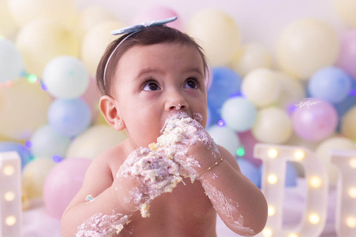 na sessão de um ano, a bebe come o bolo