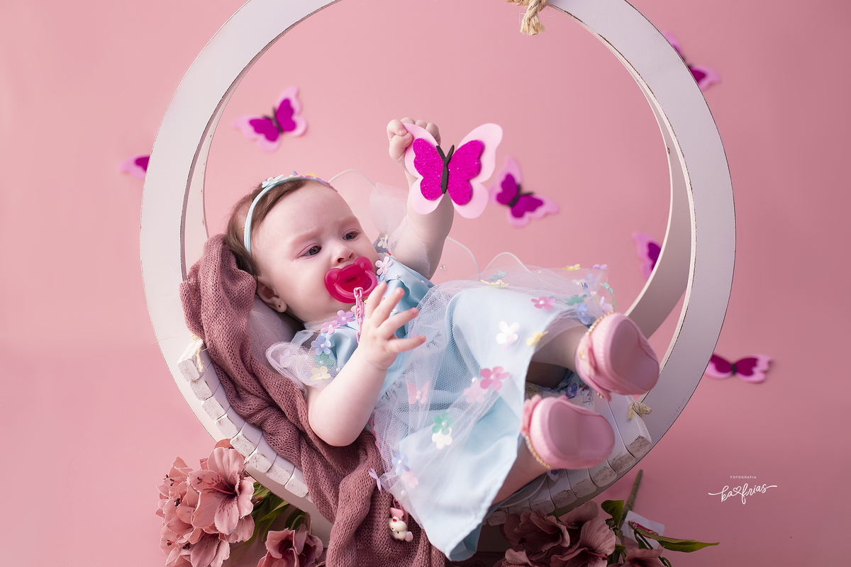 a menina segura a borboleta para as fotos mensais
